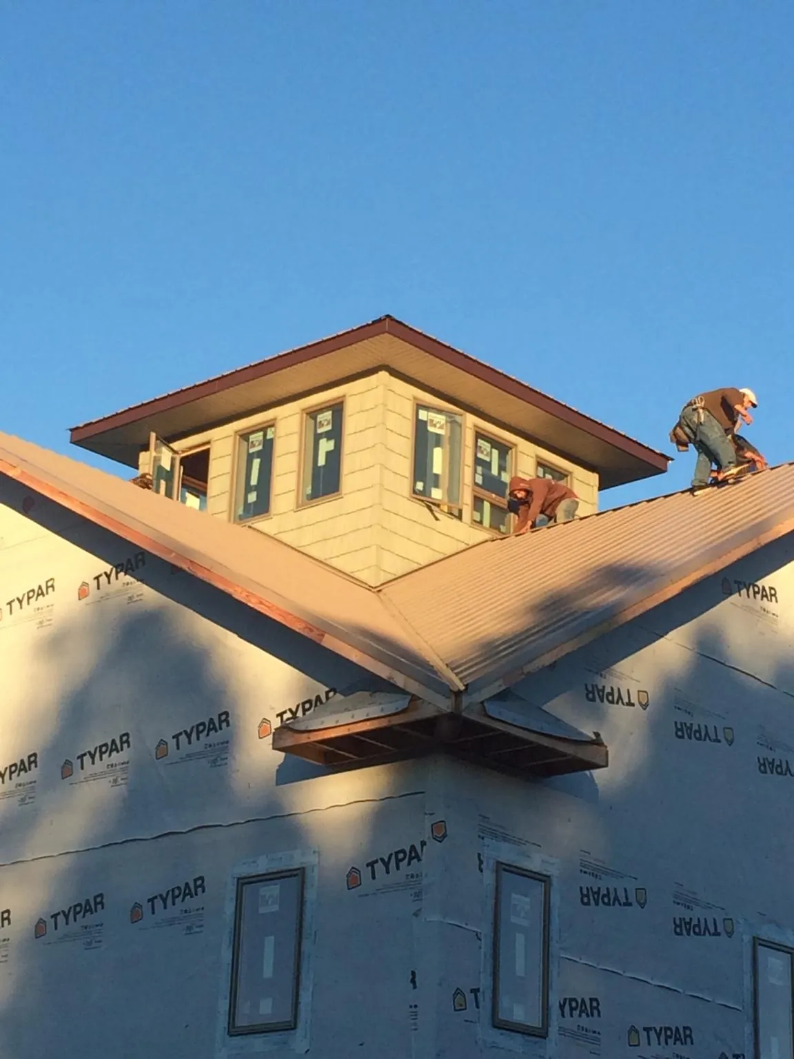 Roofers working around a rooftop cupola on a new metal roof at sunset — Roof Waterproofing in Wadsworth by Roofing Brothers